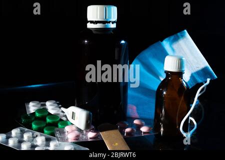 Medizinische Gläser, Thermometer, Spritze, Gaze Maske und Pillen Medikamente, Medizin auf Glas schwarzen Hintergrund Nahaufnahme. Copy space Stockfoto