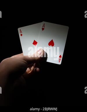 Hand halten zwei rote Asse Poker, das beste Pocket-Paar auf einem schwarzen Hintergrund kopieren Raum. Nahaufnahme Stockfoto