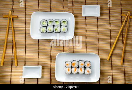 Hosomaki dünne Rollen, einfache Rollen, kleine Rollen mit Gurke, mit Lachs. Draufsicht auf einem Bambus-Hintergrund. Platz für Text, Kopierraum Stockfoto
