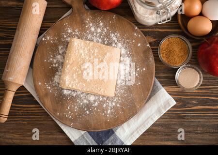 Holzbrett mit raw-flockige Teig auf Tisch Stockfoto