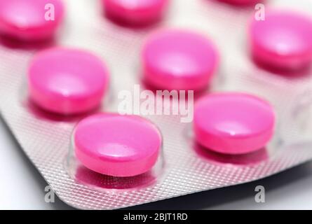 Makro-Aufnahme von rosa Pillen in Blisterpackung auf weißem Hintergrund. Stockfoto