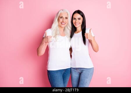 Foto von hübschen gealterten Mutter junge Tochter Damen Generation Raising Daumen Finger bis Beratung Verkauf Shopping tragen weiße T-Shirts Jeans isoliert Pastell Stockfoto