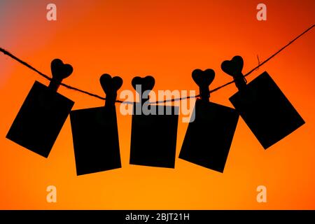 Fünf Büroklammern aus roten Wäscheklammern mit einem Herz am Seil. Liebe zum Valentinstag. Üppiger Lava Hintergrund. Kopierraum. mocap Stockfoto