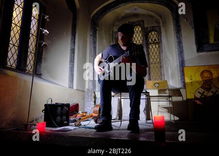 GALWAY, IRLAND - August 21 2019: Ein typischer Folksänger spielt Gitarre während eines Konzerts in einer alten Kirche. Stockfoto