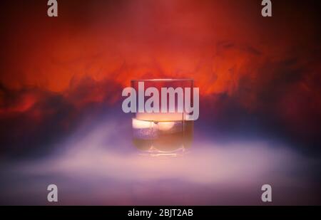 Cocktail in einem Glas rox Glas mit Eisrauch brennt auf üppigem Lava Hintergrund. Nahaufnahme Stockfoto