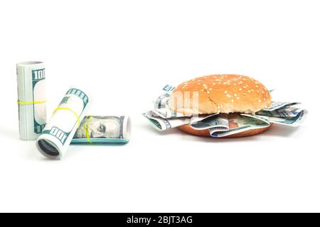 burger mit hundert Dollar-Scheinen statt Toppings und Rollen von hundert Dollar-Scheinen auf weißem Hintergrund isolieren, Seitenansicht Stockfoto