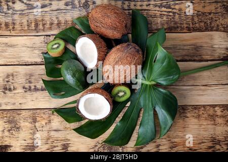 Zusammensetzung mit frischen Kokosnüssen und tropischen Früchten auf grünem Blatt Stockfoto