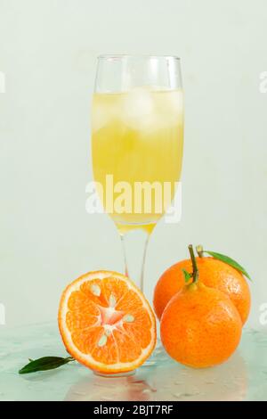 Glas Champagner mit Cocktail, Saft mit Eis Mandarinen mit lmstochkami auf Glas Licht Hintergrund Stockfoto