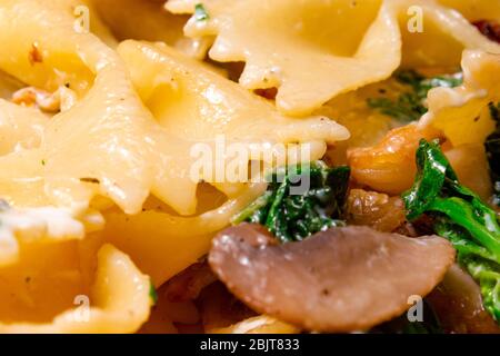 Butterfly Pasta mit gebratenen Pilzen, grünem Spinat Stockfoto