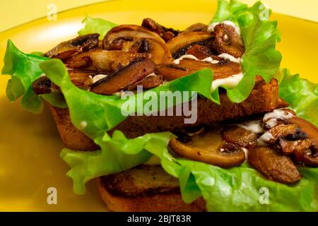 Brot Toast mit grünen Blättern, Salate, gebratene Pilze und weiße Sauce auf einem gelben Teller Stockfoto