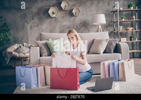 Porträt von ihr sie schön attraktiv fröhlich modisch vorsichtig reifen Dame sitzt auf Teppich suchen Kauf neuer Dinge Kleidung in modernen Industrie Stockfoto