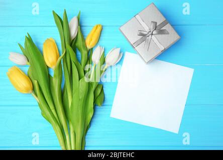 Tulpen, Blatt Papier und Geschenkbox auf Holzhintergrund Stockfoto