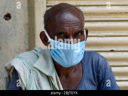 Guwahati, Assam, Indien. April 2020. Eine Arbeit mit Gesichtsmaske, die vor einem geschlossenen Geschäft während der landesweiten Sperrung nach der Coronavirus-Pandemie in Guwahati sitzt. Kredit: David Talukdar/ZUMA Wire/Alamy Live News Stockfoto