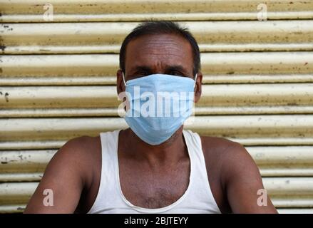 Guwahati, Assam, Indien. April 2020. Eine Arbeit mit Gesichtsmaske, die vor einem geschlossenen Geschäft während der landesweiten Sperrung nach der Coronavirus-Pandemie in Guwahati sitzt. Kredit: David Talukdar/ZUMA Wire/Alamy Live News Stockfoto