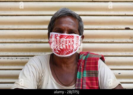 Guwahati, Assam, Indien. April 2020. Eine Arbeit mit Gesichtsmaske, die vor einem geschlossenen Geschäft während der landesweiten Sperrung nach der Coronavirus-Pandemie in Guwahati sitzt. Kredit: David Talukdar/ZUMA Wire/Alamy Live News Stockfoto