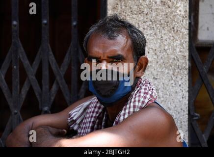 Guwahati, Assam, Indien. April 2020. Eine Arbeit mit Gesichtsmaske, die vor einem geschlossenen Geschäft während der landesweiten Sperrung nach der Coronavirus-Pandemie in Guwahati sitzt. Kredit: David Talukdar/ZUMA Wire/Alamy Live News Stockfoto