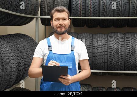 Verkäufer mit Klemmbrett in der Nähe von Reifen im Autogeschäft Stockfoto