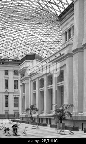 Ein Blick von der Straße auf das Innere Gemeinderat Gebäude Glasdach mit Frau sitzt an einem Tisch, um Maßstab in Madrid, Spanien zu zeigen Stockfoto