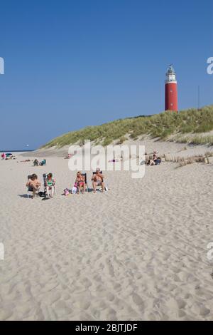 Familie genießt die Sonne am Texelstrand, im Hintergrund der typische Eierland Leuchtturm. Stockfoto