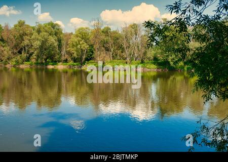 Schöne Landschaft, Sommer, der Bug Fluss fließt zwischen Feldern und Wäldern mit blauem Himmel und weißen Wolken. Polen im Sommer Stockfoto