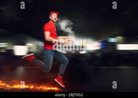 Messenger in roter Uniform läuft zu Fuß wirklich schnell zu liefern schnell heiße Pizzas gerade gebacken Stockfoto