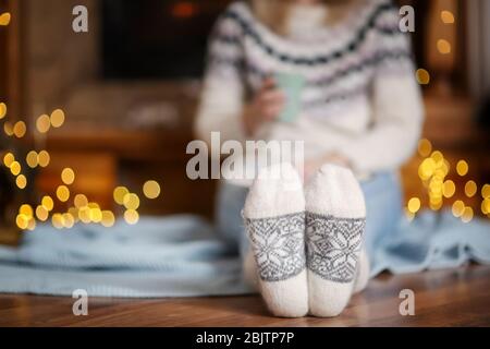 Frau in warmen Socken entspannen im Wohnzimmer für Winterferien dekoriert Stockfoto