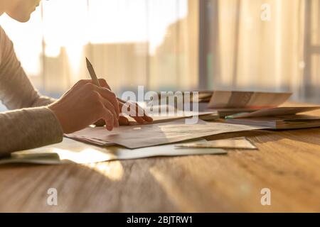 Frau arbeitet von zu Hause aus, schreibt Notizen aus Büchern in einem Dokument Stockfoto