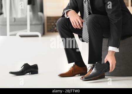 Junger Mann versucht auf Schuhe im Geschäft Stockfoto