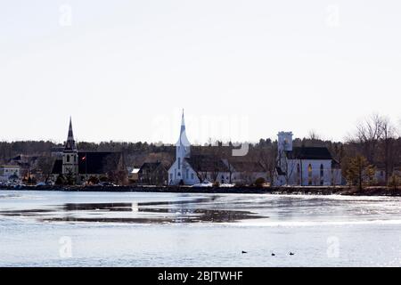 Ein Blick auf die drei Kirchen in der Mahone Bay in Nova Scotia, Kanada. Sie sind an einem Wintertag über einen teilweise gefrorenen Einlass zu sehen. Stockfoto