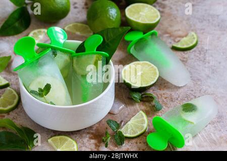 Hausgemachte Mops mit Limettensaft und Minze, Mojito-Fruchteis auf einem hellen Stein- oder Schieferhintergrund. Stockfoto
