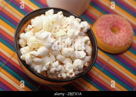 Gesalzenes Popcorn in einer Schüssel und Donut auf dem Tisch Stockfoto