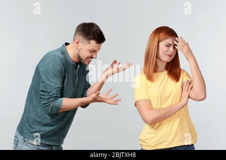 Emotionales Paar während Streit auf hellem Hintergrund Stockfoto