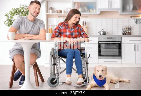 Service Hund liegt auf dem Boden in der Nähe von Frau im Rollstuhl drinnen Stockfoto