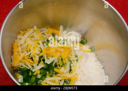 Nahaufnahme von trockenen Keks Zutaten mit zerkleinerten Käse und gehackten Jalapeno Paprika in Edelstahl Rührschüssel Stockfoto