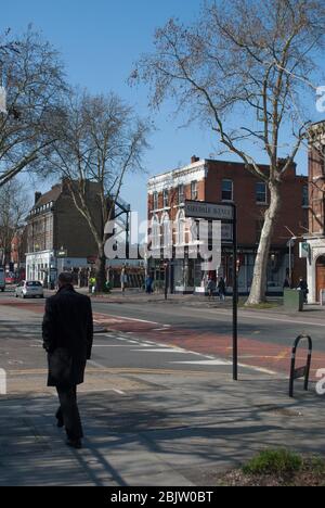 Mann in schwarzem Mantel Spaziergang Spaziergang Spaziergang Spaziergang Stadt auf Chiswick High Road, London, W4 Stockfoto