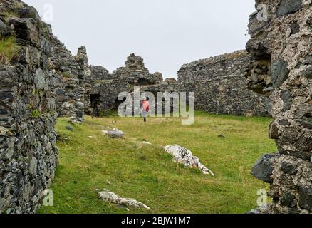 Ein Spaziergänger, der Cromwell's Barracks erkundet eine zerstörte Festung, die den Eingang zum Hafen von Inishbofin vor der Küste von Connemara im Westen Irlands bewacht Stockfoto