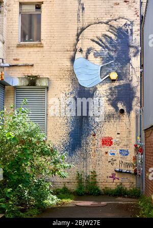 Eine Gasse in Bristol UK mit Banksy's The Girl with the Pierced Eardum, die während der Coronavirus-Pandemie von 2020 eine Gesichtsmaske trägt Stockfoto