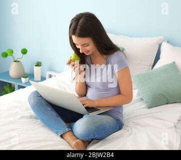 Nettes Teenager-Mädchen mit Laptop während Hausaufgaben im Schlafzimmer Stockfoto