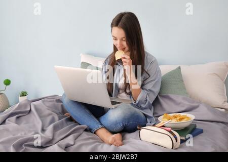 Nettes Teenager-Mädchen mit Laptop während Hausaufgaben im Schlafzimmer Stockfoto