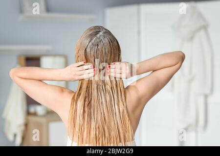 Junge Frau, die Maske auf ihr Haar, drinnen Stockfoto