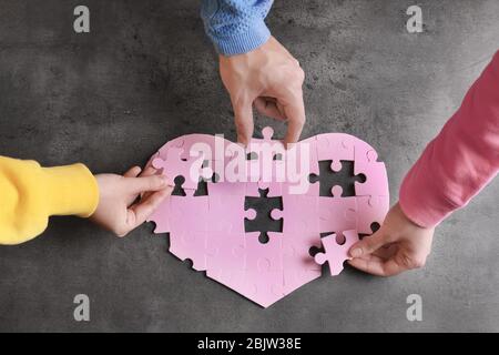 Gruppe von Menschen Abschluss Puzzle zusammen auf grauem Hintergrund. Einheitlichkeit Stockfoto