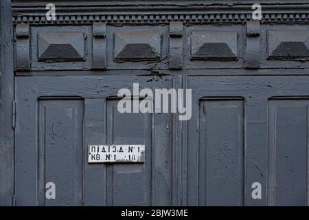 Kunstvolle Laubsägemuster der alten Holztür mit blaugrauer abblätternder Farbe und schmutzigem Namensschild "Veranda" in ukrainischer Sprache. Muster der Türverkleidungen von Stockfoto