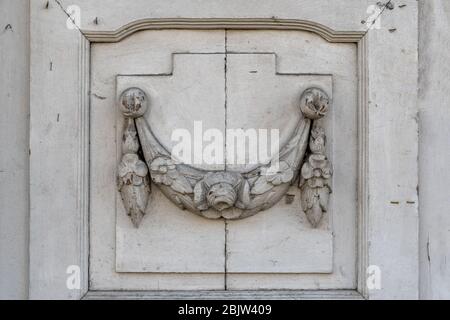 Vintage verzierten Laubsägeelement an alten hölzernen Türplatte. Schnitzereien der schmutzigen weißen Türöffnung in klassischer Architektur in Europa Stockfoto