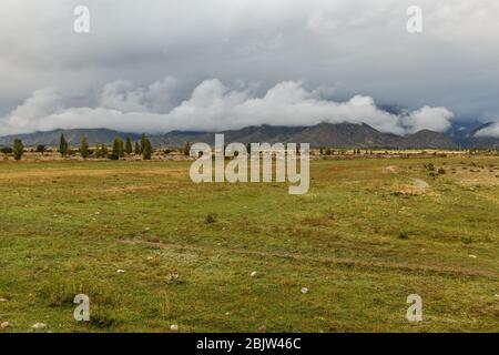 Bewölkter Himmel und niedrige Wolken in den Bergen von Kirgisistan, dem Nordufer des Issyk-Kul-Sees Stockfoto