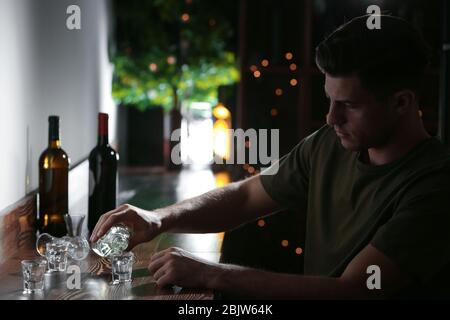 Junger Mann, der an der Bar einen Drink ins Glas gießt. Alkoholismus Problem Stockfoto