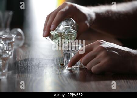 Mann gießt Getränke in Glas an der Bar, Nahaufnahme. Alkoholismus Problem Stockfoto