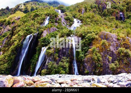 Tolle Wasserfälle am Franz Josef Gletscher in Neuseeland. Foto mit langer Belichtung für eine ausgewaschene Wirkung des Wassers aufgenommen. Stockfoto