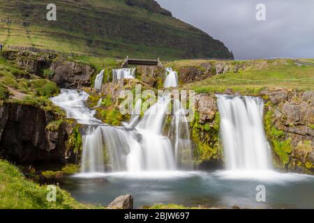 Lange Sicht auf den Kirkjufellsfoss Wasserfall, der gegenüber Kirkjufell ('Kirchberg') auf der Halbinsel Snæfellsnes, Island liegt. Stockfoto