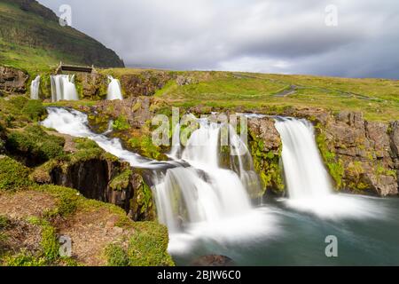 Lange Sicht auf den Kirkjufellsfoss Wasserfall, der gegenüber Kirkjufell ('Kirchberg') auf der Halbinsel Snæfellsnes, Island liegt. Stockfoto