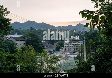 Chongqing, China - August 2019 : Alte baufällige Gebäude in den Vororten der Stadt Chongqing mit Berggipfeln im Hintergrund Stockfoto
